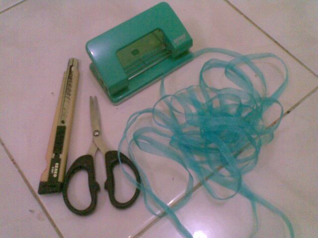 siapkan cutter, pita berbagai warna, gunting dan alat pelubang kertas