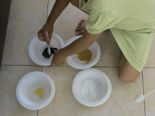 menggunakan sendok plastik untuk mencampur warna