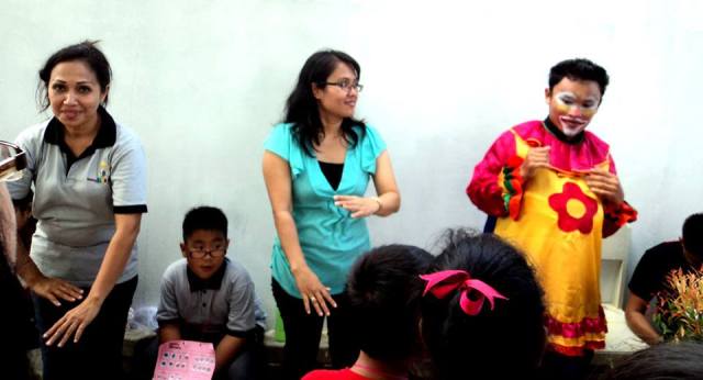 asisten pak badut saat mengatasi antrian yang sangat panjang dari pengunjung pos ini, Ibu Ellen. 