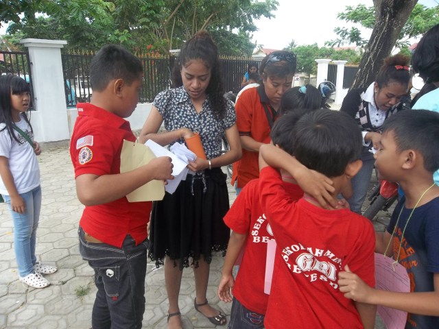 TAMPAK PENJAGA POS SEDANG MENGAMBILKAN STIKER PADA PESERTA YANG BERHASIL MENYUSUN KALIMAT DENGAN BAIK